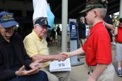 A youth member of the Young Marines greets veterans at the Pearl Harbor memorial site during the 2011 Pearl Harbor Memorial Parade in Honolulu.